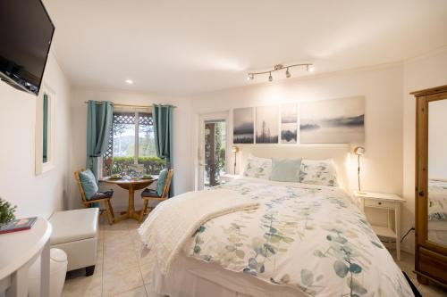 a bedroom with a bed and a table and chairs at Enchanter Ocean View Suites in Madeira Park