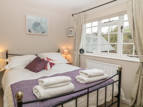 a bedroom with a bed with towels on it at Robyn Cottage in Budleigh Salterton