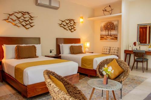 a hotel room with two beds and a table at Le Muuch Hotel Boutique in Valladolid