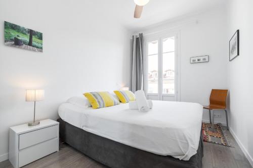 - une chambre blanche avec un grand lit et des oreillers jaunes dans l'établissement Cosy 2 Bdrs-Terrace near GaribaldiVieux NicePort, à Nice