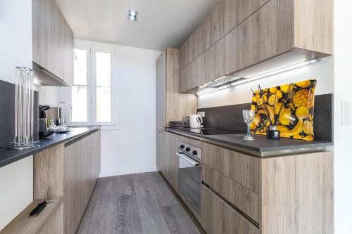 eine Küche mit Holzschränken und einer Arbeitsplatte in der Unterkunft Cosy 1 Bdr near Garibaldi Square - Top Floor & AC in Nizza
