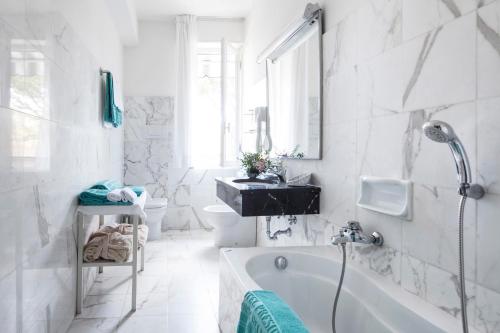 Baño blanco con bañera y lavamanos en President Hotel en Forte dei Marmi