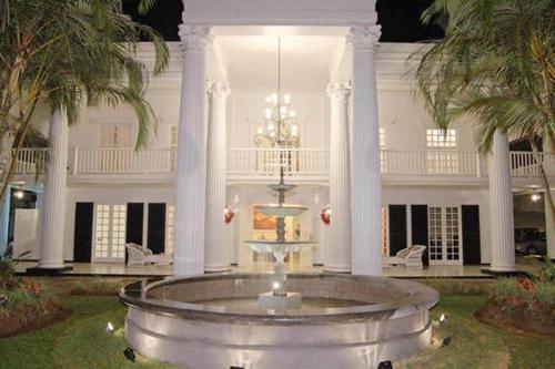 a large white mansion with a fountain in the yard at Fogo Resort in Escazu