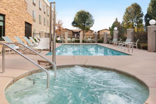a swimming pool with chairs and a hot tub at Holiday Inn Express & Suites Merced - Yosemite Natl Pk Area by IHG in Merced