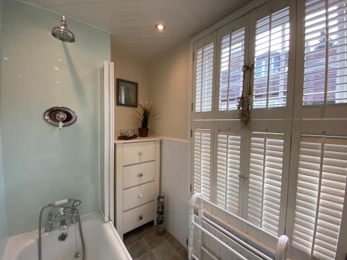 a bathroom with a tub and a window with shutters at Starboard Light in Lymington