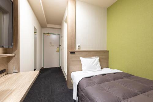 Habitación pequeña con cama y pared verde en R&B Hotel Higashi Nihonbashi, en Tokio