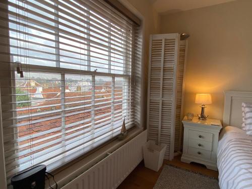 a bedroom with a window with a bed and a lamp at Starboard Light in Lymington