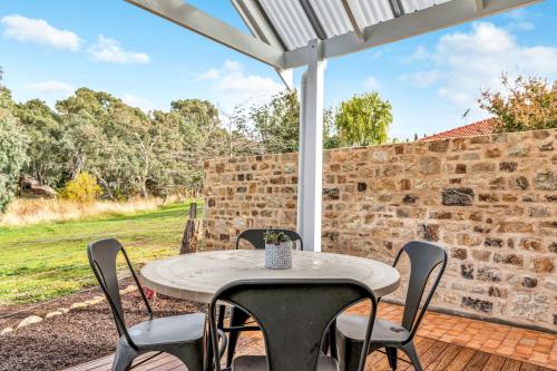 a table and chairs on a patio with a stone wall at Grandview Accommodation - The Elm Tree Apartments in Mount Barker