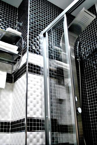 a glass shower in a bathroom with black tiles at Madrid City Rooms in Madrid