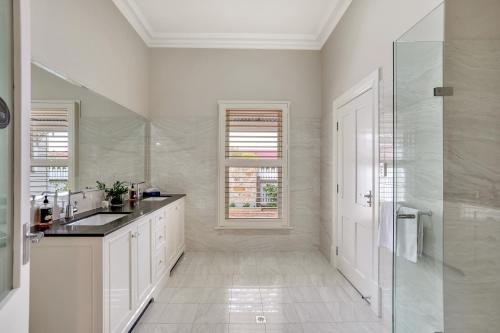 uma casa de banho branca com um lavatório e um chuveiro em Grandview Accommodation - The Elm Tree Apartments em Mount Barker