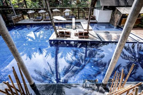 a swimming pool with chairs and a reflection in the water at Ayara Villas - SHA Extra Plus in Khao Lak