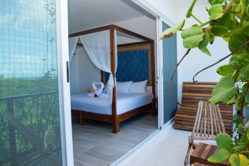 1 dormitorio con cama con dosel en el balcón en Oceanview Luxury Suite Steps from Quinta Avenida Balcony Infinity pool HMoon, en Playa del Carmen