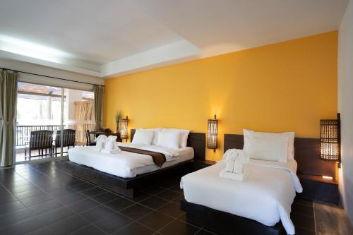 two beds in a hotel room with yellow walls at Ayara Villas - SHA Extra Plus in Khao Lak