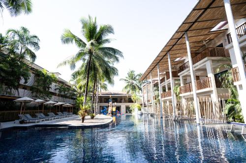 a pool in the middle of a building with palm trees at Ayara Villas - SHA Extra Plus in Khao Lak