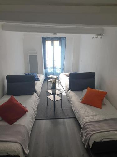 Cette chambre comprend 3 lits avec des oreillers et une table. dans l'établissement Gîte d'Etape Les Arcades, à Belvédère