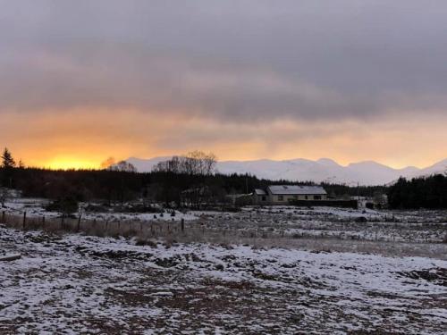 a snow covered field with a house in the background at Stronaba Croft Cabins in Spean Bridge