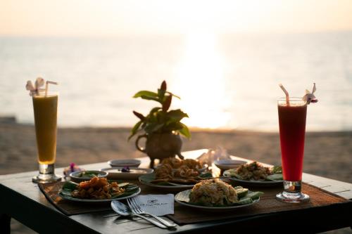 a table with plates of food and two drinks at Ayara Villas - SHA Extra Plus in Khao Lak