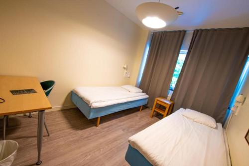 a hospital room with two beds and a desk at Vandrarhem Kvarntorget in Uppsala