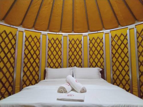 a bed in a yurt with two towels on it at Rick Resort Teluk Intan in Teluk Intan