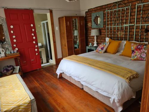 a bedroom with a large bed and a red door at Mirabel Guesthouse in Parys