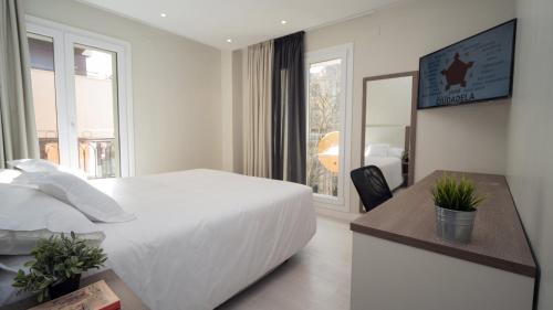 a white bedroom with a large bed and a window at Hotel Ciudadela Pamplona in Pamplona