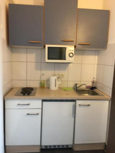 a small kitchen with white cabinets and a microwave at Pension Alis Augsburg in Augsburg