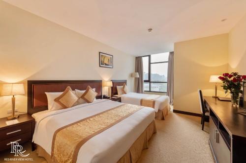 a hotel room with two beds and a window at Red River View Hotel in Lao Cai