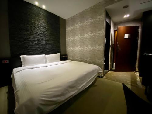 a bedroom with a white bed and a wall at The Tree House in Kaohsiung