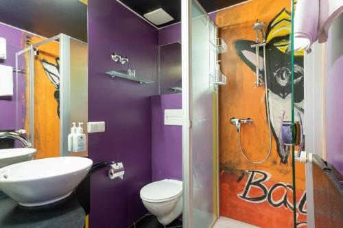 a bathroom with a toilet and a shower with purple walls at ART-Hotel Braun in Kirchheimbolanden