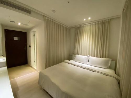 a bedroom with a large white bed and a window at The Tree House in Kaohsiung