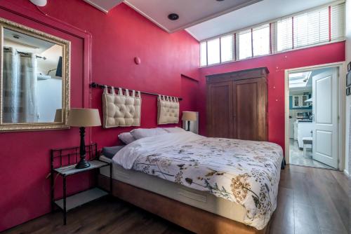 een slaapkamer met rode muren en een bed met een spiegel bij Job Baster Gastenverblijf in Zierikzee
