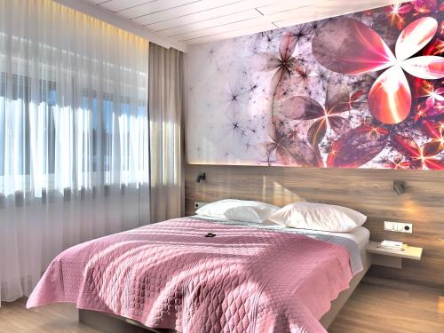 a bedroom with a bed with a pink blanket at ART-Hotel Braun in Kirchheimbolanden