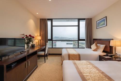 a hotel room with two beds and a flat screen tv at Red River View Hotel in Lao Cai