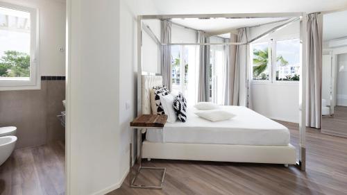 Biała sypialnia z łóżkiem z baldachimem i łazienką w obiekcie PORTOVERDE BEACH VILLA 12, Emma Villas w mieście Misano Adriatico