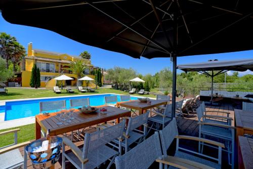 a patio with tables and chairs next to a pool at Beautiful 9-Bed Villa in Gouvia with Tennis Court in Gouvia