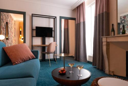 Leonardo Boutique Hotel Paris Opera في باريس: غرفة معيشة مع أريكة زرقاء ومدفأة