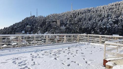a snow covered hill with a fence and a mountain at Nomadic Inn in Dharamshala