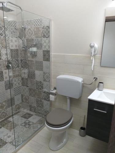 a bathroom with a toilet and a glass shower at Imperial Park in Raffadali