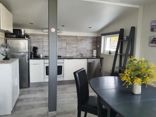 une cuisine avec une table avec des chaises et un réfrigérateur dans l'établissement Chalet ALOHA, à Saint-Côme-de-Fresné