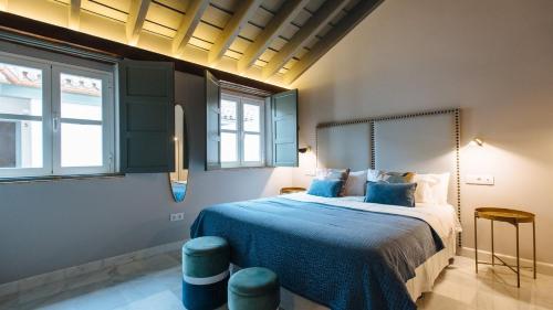 a bedroom with a bed with blue sheets and windows at Magno Apartments Rocío in Seville