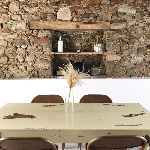 une table avec des chaises et un mur en pierre dans l'établissement Le Mottay Guesthouse, à Saint-Père-en-Retz