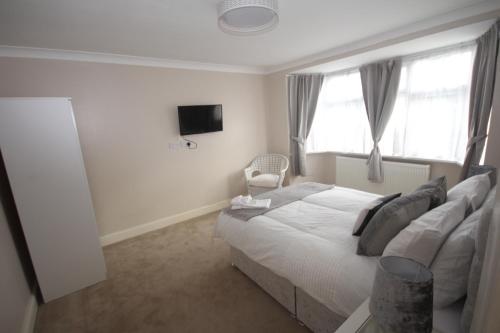 a bedroom with a bed and a tv and windows at Kenton House in Wealdstone
