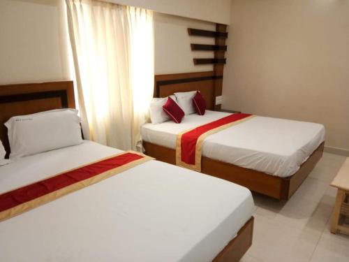 two beds in a hotel room with two beds at HLVGRANDINN in Bangalore