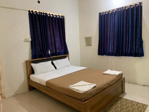 a bedroom with a bed with blue curtains at The Cottage - by Chandralok Homestays in Kolhapur