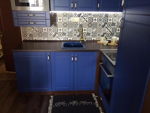 cocina con armarios azules y encimera negra en Apartment Perfect en Pomorie
