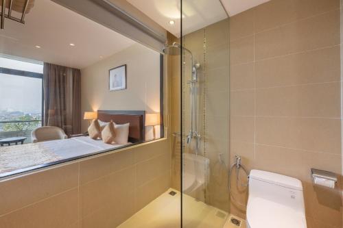 a bathroom with a shower and a toilet and a bedroom at Red River View Hotel in Lao Cai
