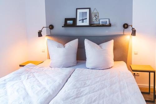 1 cama con sábanas blancas y almohadas en una habitación en Fewo Fähr-wind 150m vom Strand en Altefähr