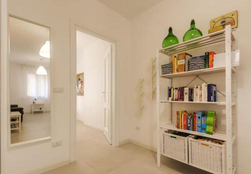una stanza con una libreria con libri e uno specchio di Magnolia - Civico 96 ad Alghero