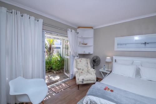 a bedroom with a bed and a chair and a window at Apartment Melkbos Moments in Melkbosstrand
