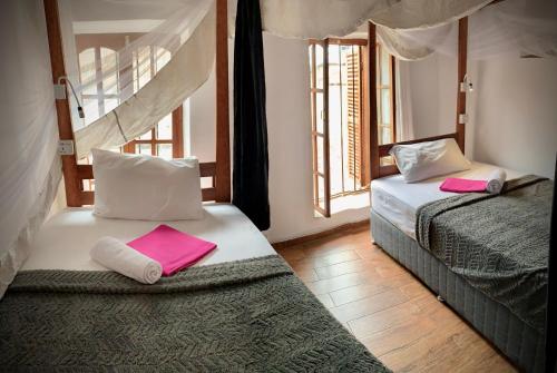 a bedroom with two beds with pink towels on them at Stone Town House in Zanzibar City